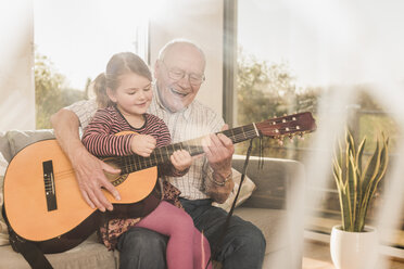 Großvater und Enkelin spielen zusammen Gitarre - UUF09555