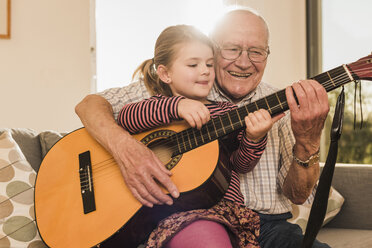 Großvater und Enkelin spielen zusammen Gitarre - UUF09557