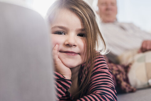 Kleines Mädchen sitzt mit ihrem Großvater auf der Couch - UUF09560
