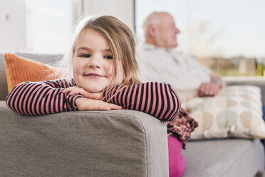 Kleines Mädchen sitzt mit ihrem Großvater auf der Couch - UUF09561