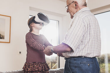 Großvater hält seine Enkelin und benutzt eine VR-Brille - UUF09562