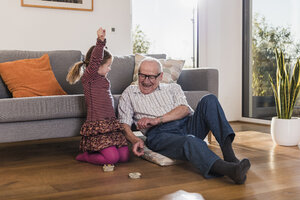 Großvater und Enkelin spielen Memory, Mädchen feiert den Sieg - UUF09571