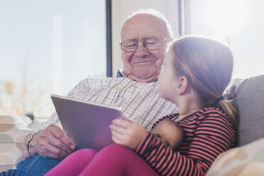 Grandfather reading out story for his granddaughter, using ebook - UUF09573