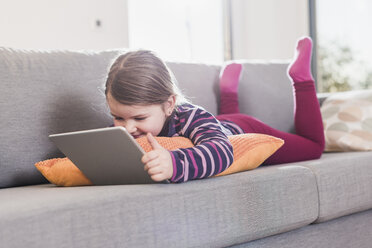 Little girl using digital tablet, lying on couch - UUF09577