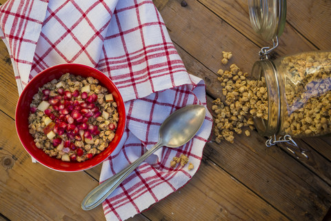 Bowl of granola with pomegranate seed and red apple on wood stock photo