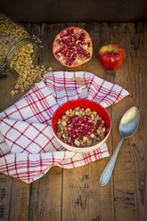 Bowl of granola with pomegranate seed and red apple on wood - LVF05752
