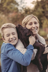 Junge und Frau kuscheln mit Labrador Retriever - MFF03394