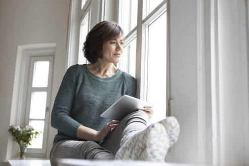 Frau mit Tablet und Blick aus dem Fenster - RBF05342