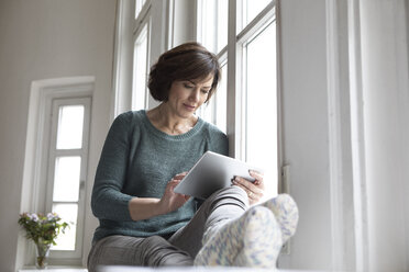 Frau benutzt Tablet am Fenster - RBF05343