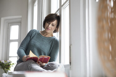 Woman reading book at the window - RBF05345