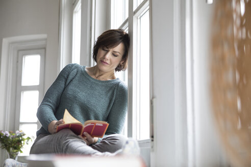 Frau liest Buch am Fenster - RBF05345