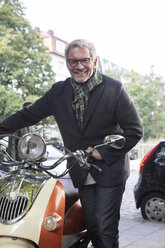 Smiling mature man with motor scooter - RBF05349