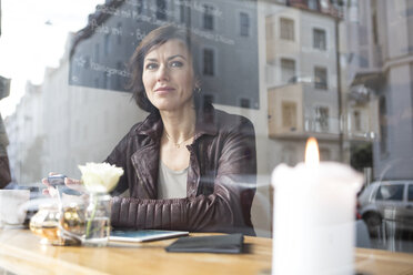 Woman in a cafe looking out of window - RBF05364