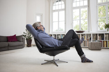 Entspannter reifer Mann zu Hause auf einem Stuhl sitzend - RBF05374