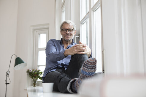 Entspannter reifer Mann zu Hause am Fenster sitzend - RBF05379