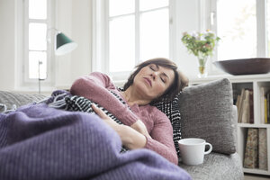Frau mit Bauchschmerzen auf dem Sofa liegend - RBF05396