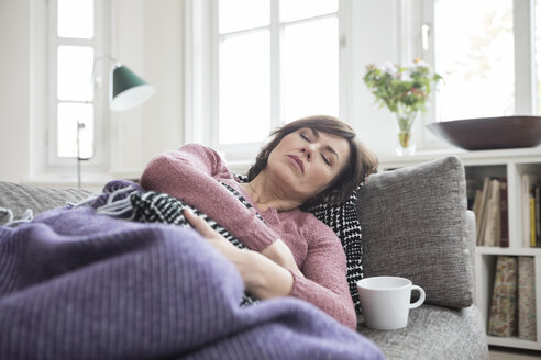 Woman with stomach ache lying on the sofa - RBF05396