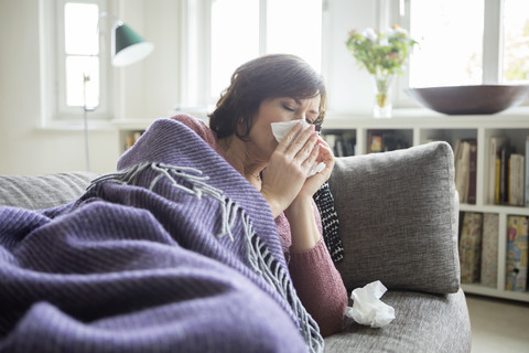 Woman having a cold lying on the sofa stock photo