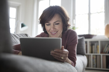 Woman at home lying on the sofa using tablet - RBF05404