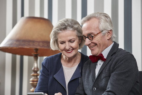 Glückliches Seniorenpaar nutzt Smartphone zu Hause, lizenzfreies Stockfoto