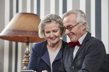 Glückliches Seniorenpaar nutzt Smartphone zu Hause - RHF01683