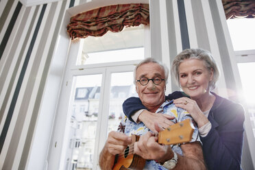 Happy senior couple with man in Hawaiian shirt playing ukulele - RHF01691
