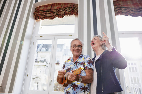 Glückliches älteres Paar mit Mann im Hawaiihemd, der Ukulele spielt - RHF01694
