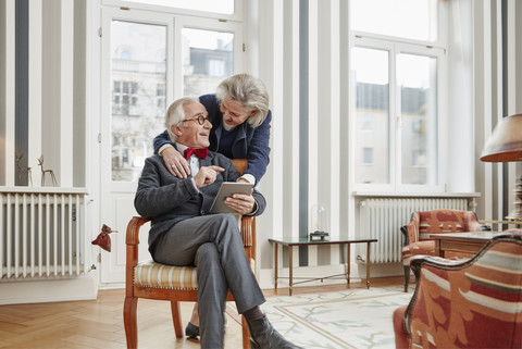 Glückliches Seniorenpaar nutzt Tablet zu Hause, lizenzfreies Stockfoto