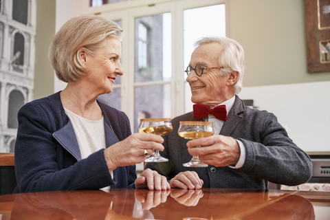 Lächelndes Seniorenpaar stößt mit Sektgläsern an, lizenzfreies Stockfoto