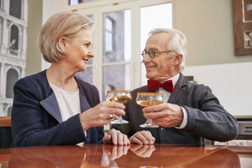 Lächelndes Seniorenpaar stößt mit Sektgläsern an - RHF01716