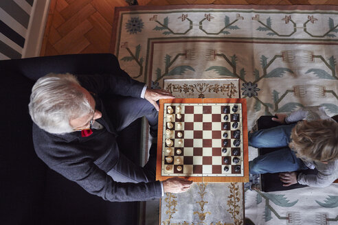 Großvater und Enkel spielen Schach im Wohnzimmer - RHF01717