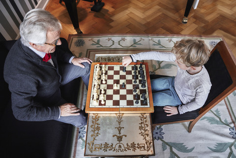 Grandfather and grandson playing chess in living room stock photo