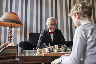 Grandfather and grandson playing chess in living room - RHF01724