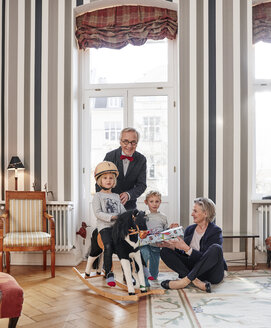 Großeltern und Enkelkinder mit Schaukelpferd und Geschenk - RHF01746