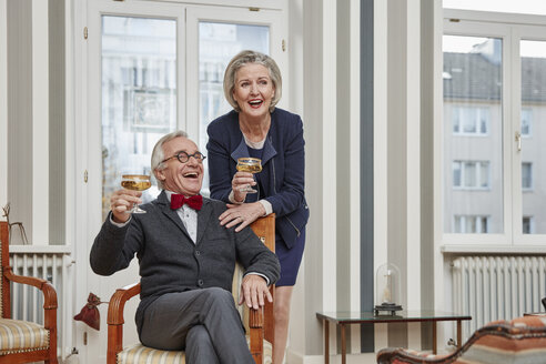 Glückliches Seniorenpaar trinkt zu Hause Champagner - RHF01754