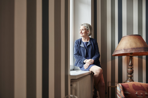 Ältere Frau schaut aus dem Fenster, lizenzfreies Stockfoto