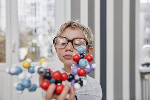 Junge mit übergroßer Brille, der ein molekulares Modell betrachtet - RHF01772