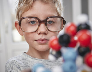 Boy wearing oversized glasses looking at molecular model - RHF01774