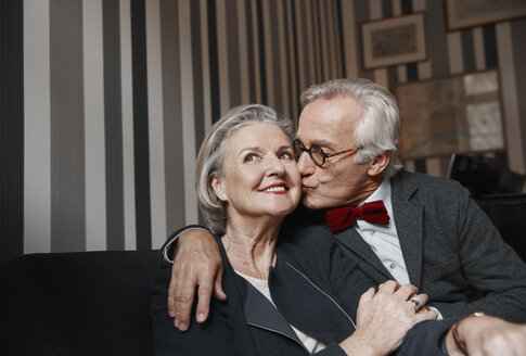 Älterer Mann küsst Frau auf Couch - RHF01778