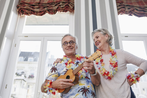 Glückliches älteres Paar mit Mann im Hawaiihemd, der Ukulele spielt - RHF01789