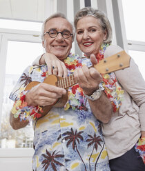 Glückliches älteres Paar mit Mann im Hawaiihemd, der Ukulele spielt - RHF01790
