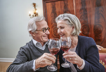 Smiling senior couple clinking red wine glasses - RHF01797