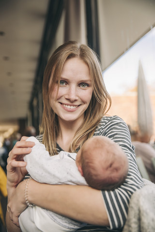 Portrait of smiling mother holding baby in cafe stock photo