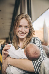Portrait of smiling mother holding baby in cafe - MFF03410