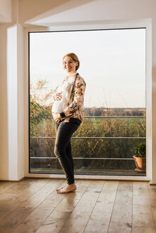 Schwangere Frau am Fenster stehend - UUF09622