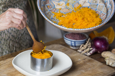 Woman arranging raw pumpkin noodles and onion pesto on plate - ALBF00068