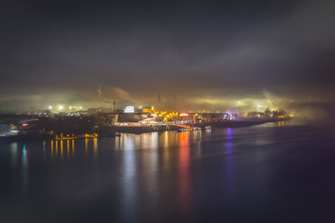 Deutschland, Hamburg, Blick auf den Hafen mit beleuchtetem Musicaltheater im Nebel bei Nacht - NKF00470