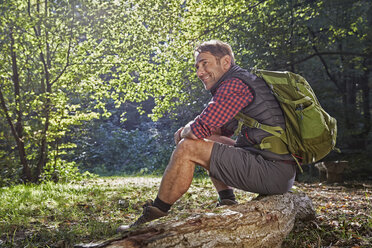 Wanderer im Wald auf einem Baumstamm sitzend - FMKF03324