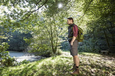 Wanderer im Wald, der mit den Händen in den Taschen die Landschaft betrachtet - FMKF03328