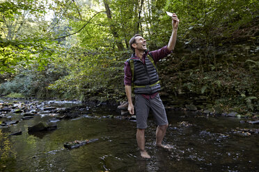 Wanderer im Wald, der am Bach steht und ein Selfie macht - FMKF03335